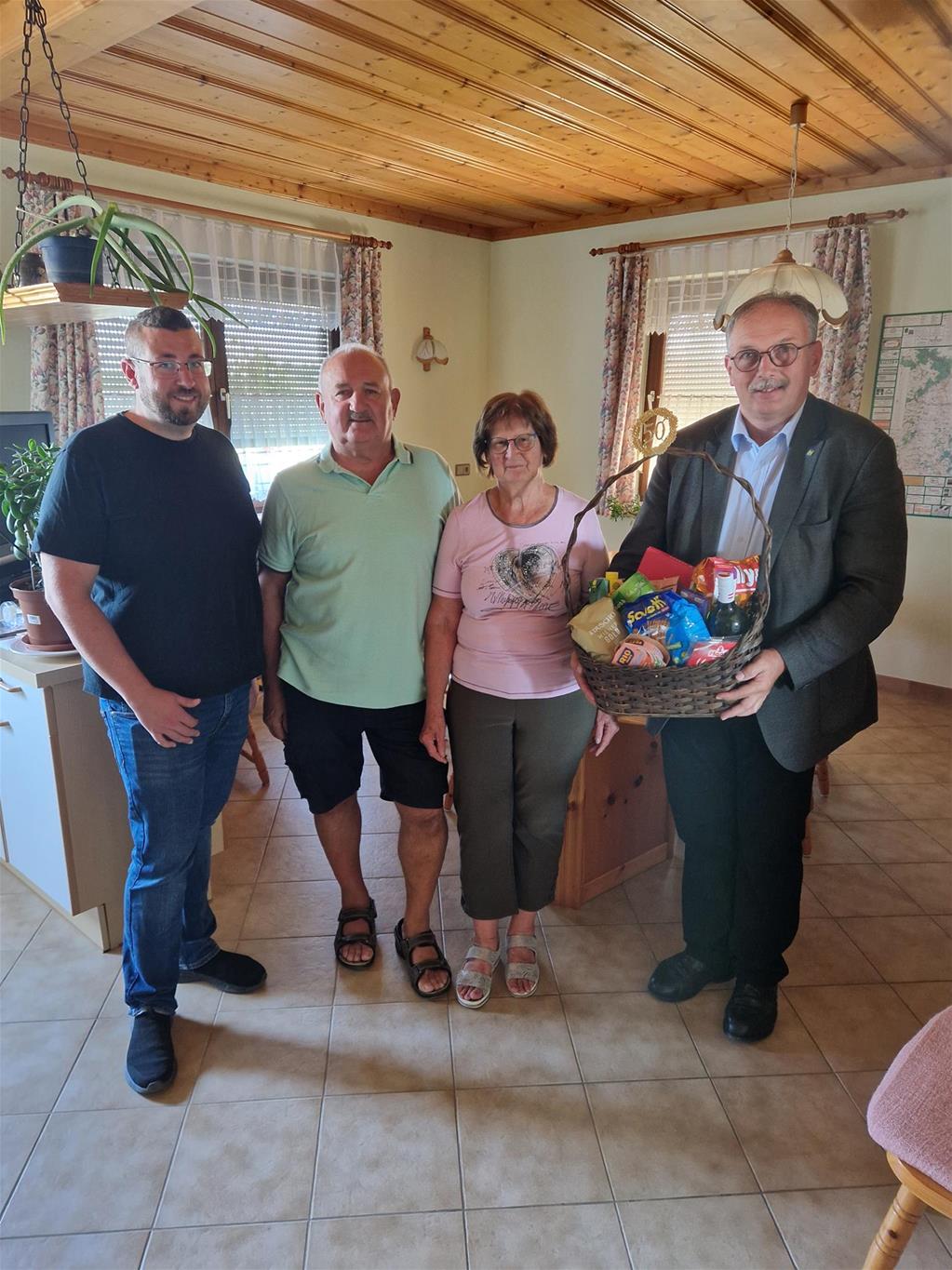 Auf dem Bild überreicht Bürgermeister Hogl mit Ortsvorsteher Benjamin Piglmaier einen Geschenkkorb an das Ehepaar Gerhard und Martha Völker anlässlich ihrer Goldenen Hochzeit